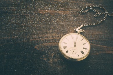 new year clock. old pocket watch on a wooden background in vintage tones. new year's background with hours over time 23:55.