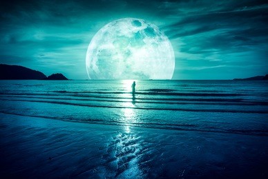 super moon. colorful sky with bright full moon over seascape and silhouette of woman standing in the sea . serenity nature background, outdoor at gloaming. the moon taken with my own camera.