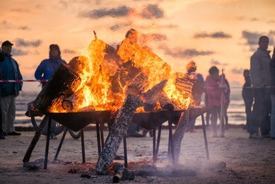 large burning bonfire with soft glowing flame and sparkles flying all around. romantic summer evening, people relaxing and enjoying calmness at the seaside during the night of ancient lights