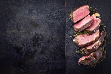 barbecue dry aged kobe rib eye steak as close-up on a burnt board with copy space left 