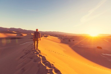 hiker in sand desert. sunrise time.