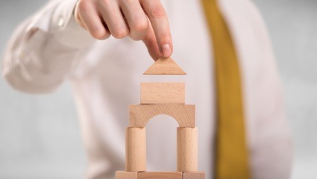 young handsome businessman using wooden building blocks 