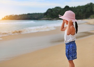 adorable little girl wear straw hat relax at the beach.