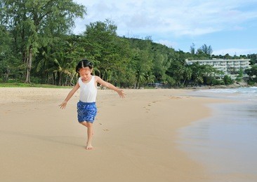 little asian child girl running on the sea beach.