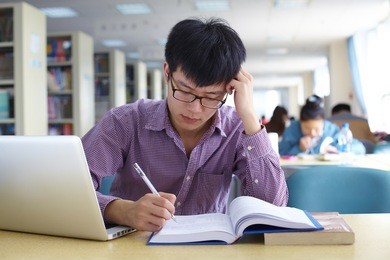 one young chinese male college student study in the library with laptop 