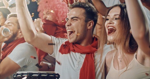 group of fans cheer for their team victory on a stadium bleachers. they wear casual fan clothes.