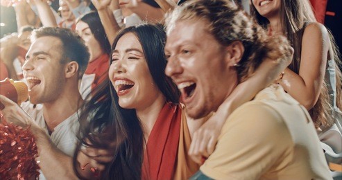 group of fans cheer for their team victory on a stadium bleachers. they wear casual fan clothes.