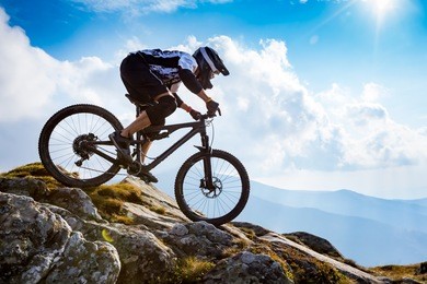 a man is riding enduro bicycle, on the background of mountains and blue sky. beautiful summer day.