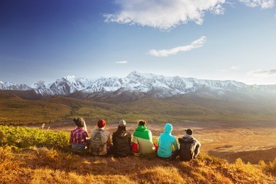 group of friends having rest on the top of mountain on backdrop of glacier. travel concept with space for text
