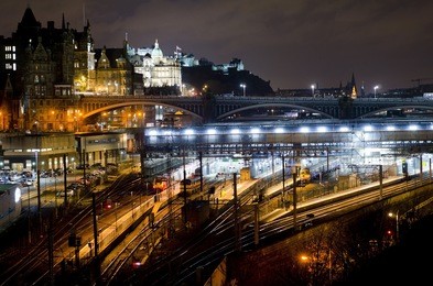 central edinburgh from regent road at night - vista including waverley train station, north bridge, bank of scotland building and edinburgh castle