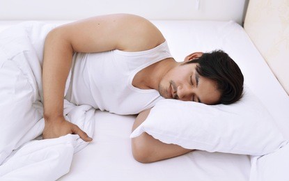 young asian man sleeping comfortably in bed