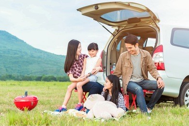 drive in the vacations family; asian family are happy sitting in the open trunk of a car;  travel nature trip.