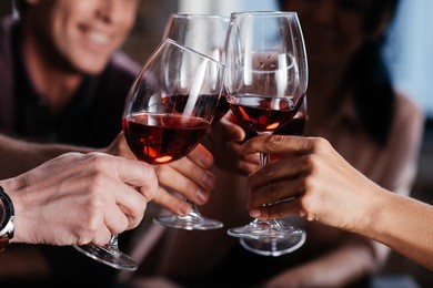 cropped shot of friends clinking glasses of red wine