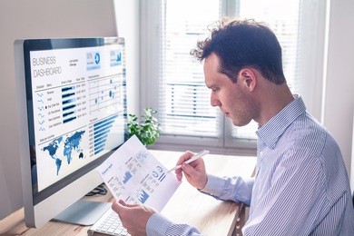 businessman working with dashboard and key performance indicator (kpi) metrics, business intelligence (bi) graph and charts and financial report data with computer in office