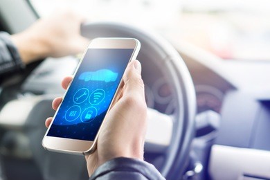 internet of things (iot) mobile app in smart phone for modern car. hand holding smartphone with futuristic adas system. vehicle with autonomous self control. interior view in cockpit.