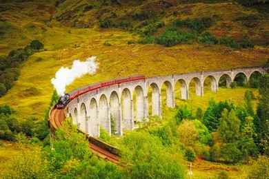 glenfinnan railway viaduct in scotland with the jacobite steam train passing over.