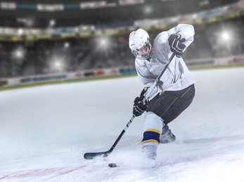 ice hockey player in action kicking with stick in front of big modern hockey arena with flares and lights