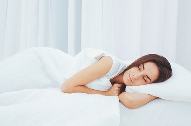 beautiful young woman sleeping in a white bed in a large spacious bedroom