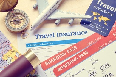 travel insurance, transportation or aviation concept : top view of travel insurance application form, first class boarding passes, a map, monocular, tag, compass, white model air plane on a wood floor
