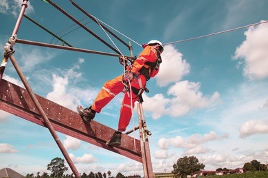 workers up high with safety equipment and safety belts, construction workers wearing safety harness belt high place on monotone.