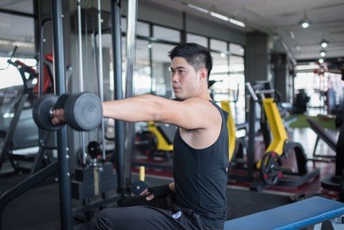 young adult  man working out in gym used dumbbell