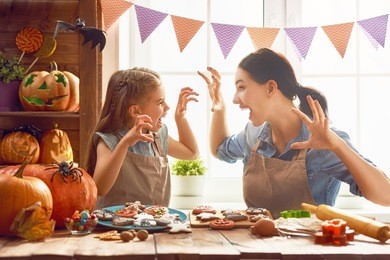 mother and her daughter having fun at home. happy family preparing for halloween. mum and child cooking festive fare in the kitchen.