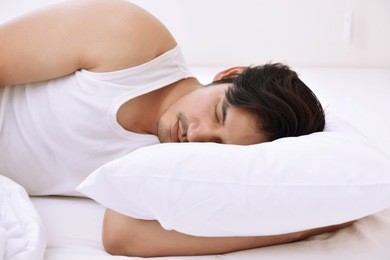 young asian man sleeping comfortably in bed