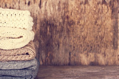 a stack of woolen sweater, plaid. warm clothing. home atmosphere, winter clothing. gray, white and brown sweater. warm and cozy. knitted clothes. cozy atmosphere.