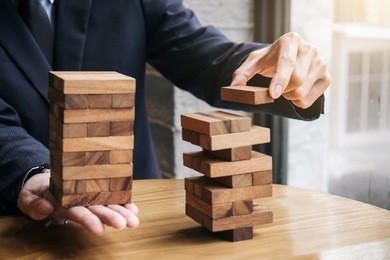 alternative risk concept, plan and strategy in business, young intelligent businessman playing the wood game, hands of executive cooperate placing wood block on the tower, collaborative management.
