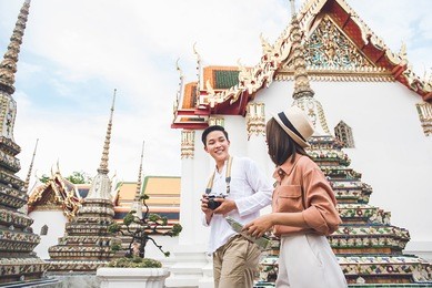 young asian photographer tourist with his girlfriend visiting thai temple, wat phra chetuphon (wat pho), in bangkok  thailand on summer holidays