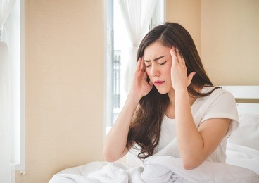 young beautiful asian woman headache on white bed, sad, migraine stressed, crying, disappointed feeling in the morning