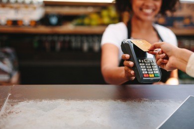 customer making wireless or contactless payment using credit card. smiling cashier accepting payment over nfc technology.