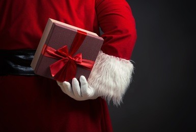santa claus holding a present behind his back, close up