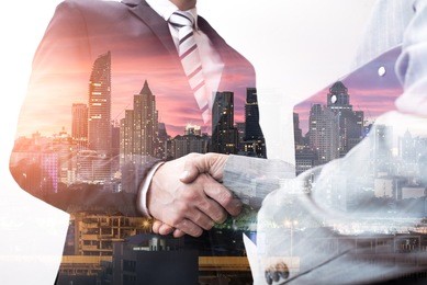 the double exposure image of the businessman handshaking with another one during sunrise overlay with cityscape image. the concept of modern life, business, city life and partnership.