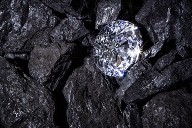 a single solitaire diamond in amongst some pieces of coal. 