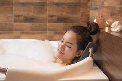 bathing woman relaxing in bath smiling relaxing. multicultural asian / caucasian young woman in bathtub.