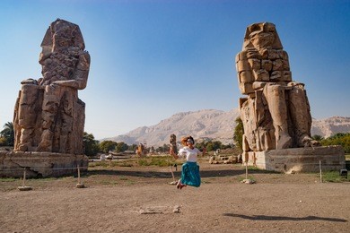 junping near the ruins of statues in luxor, egypt
