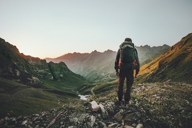 man hiking at sunset mountains with heavy backpack travel lifestyle wanderlust adventure concept summer vacations outdoor alone into the wild