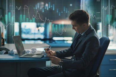 trader, a player in the securities market on the forex or forbes. elegant stylish successful in a suit in the office. on glass is large chart of the fall and increase in exchange rate of currencies