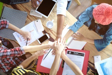 top view of multiethnic diverse group of young creative business people joining hands with colleagues together at meeting time for develop job to success, business co-working teamwork concept