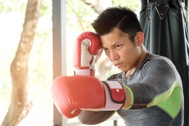 asian handsome sportman who has perfect body exercise by boxing with red boxing gloves at gym, box fighters training sport concept