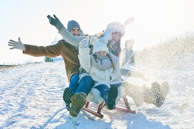 family driving sled on the snow and having fun in winter