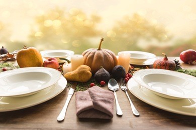 four plates with cutlery and autumnal vegetables on wooden table