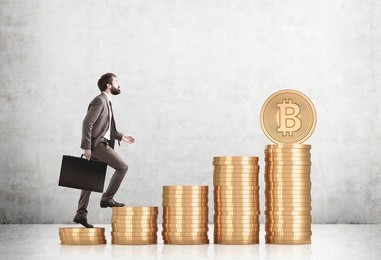 side view of a bearded businessman in a brown suit climbing stacks of bitcoins in a concrete room. mock up