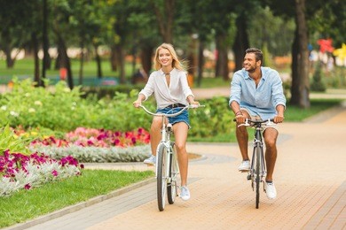 happy young couple riding bicycles together in park