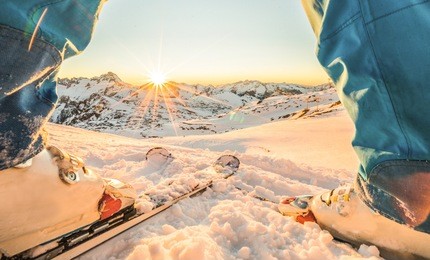 skier athlete standing in front of wonderful sunset in ski resort - winter extreme sport concept with person on top of the mountain ready to ride down - focus on intersection skis