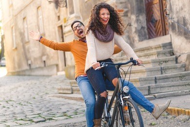 happy young couple having fun riding a bicycle on sunny autumn day in the city.