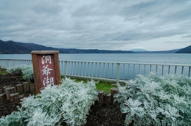 cloudy view of the infamous lake toya. the lake is a volcanic caldera lake in shikotsu-toya national park, located in hokkaid, japan. text on signboard read as "lake toya"