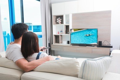 happy family watches television while sitting on the sofa.