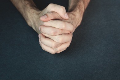 praying hands on a blue background.
